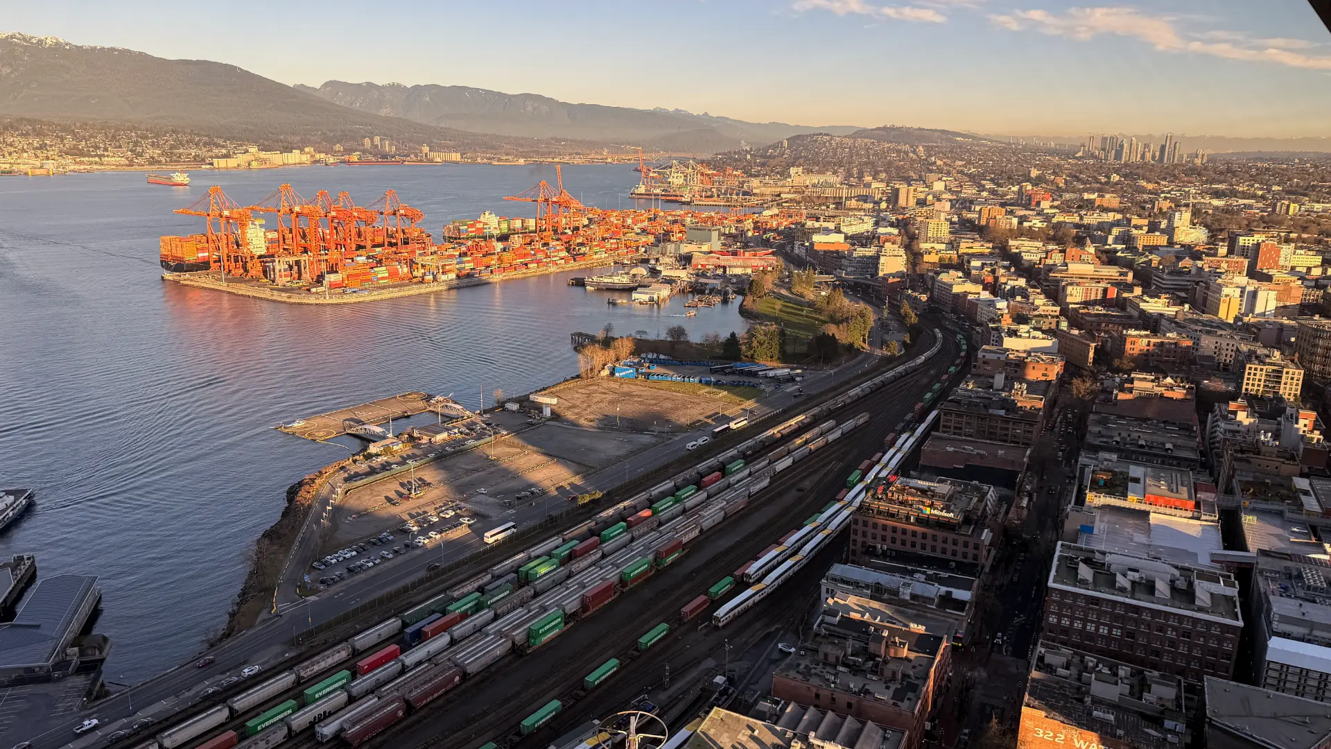 Luftaufnahme eines Containerhafens mit Kränen und Bahnanlagen zur goldenen Stunde