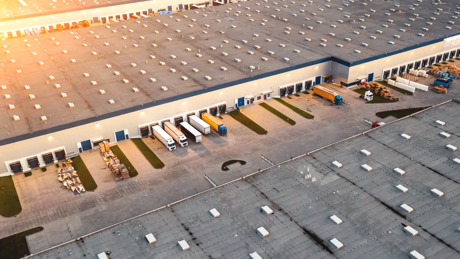 Luftaufnahme eines großen Logistikgebäudes mit Laderampen und Parkplätzen