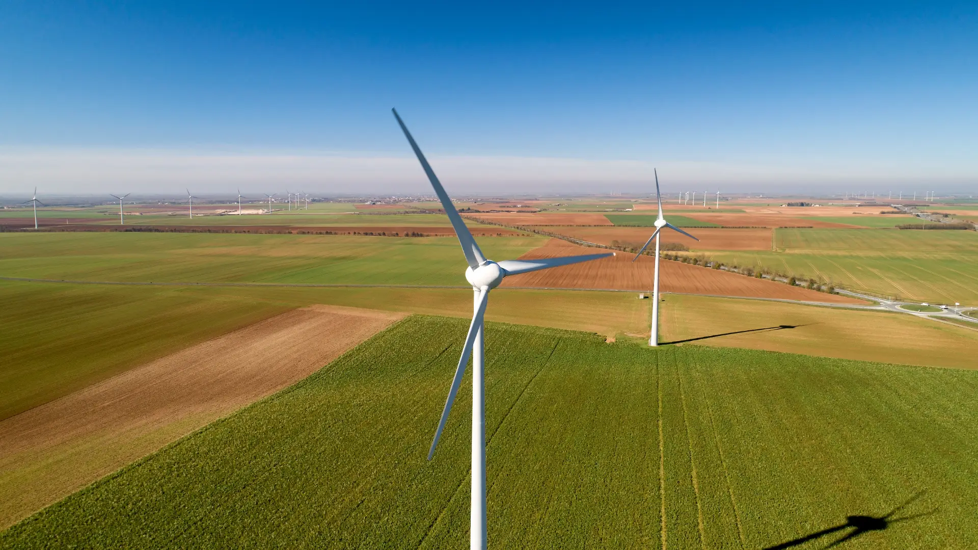 Luftaufnahme einer Windkraftanlage auf einem Feld unter blauem Himmel